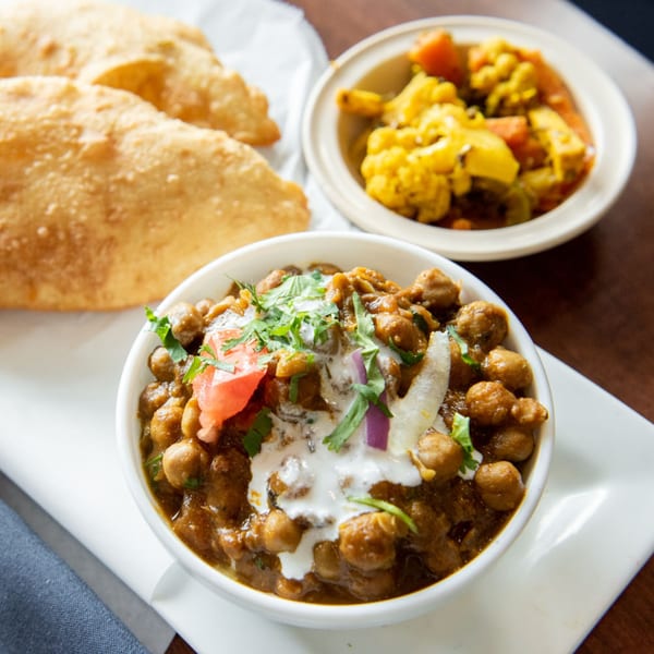 Tandoori Flame's chana masala with cream, tomato, onion, cilantro, puri bread, and mixed vegetables.