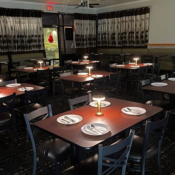 Empty dining room at Tandoori Flame with set tables, chairs, and decorative curtains.