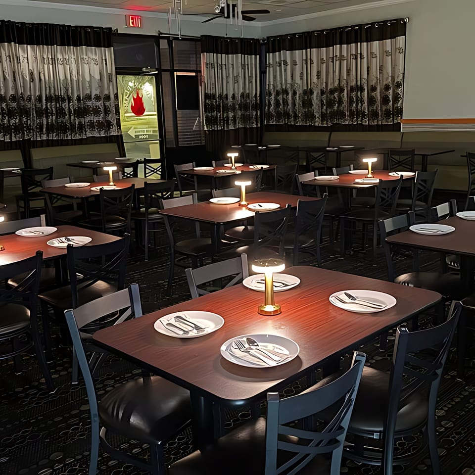 Empty dining room at Tandoori Flame with set tables, chairs, and decorative curtains.