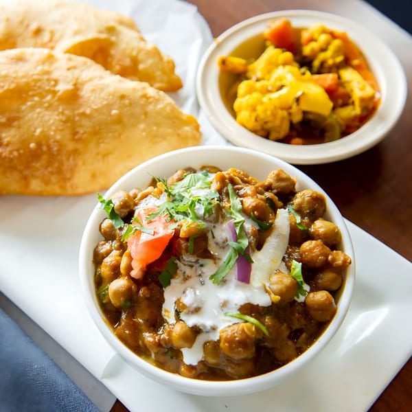 A bowl of chana masala with puri bread and a side of mixed vegetables from Tandoori Flame.